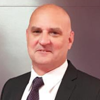 A headshot photo of a man smiling